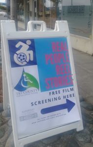 A sandwich sign on the sidewalk shows with an arrow where the film screening event will take place